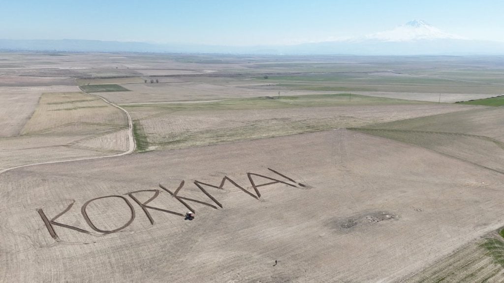 Aksaraylı çiftçiden 12 Mart’a özel mesaj: Tarlasına ‘Korkma’ yazıdırdı